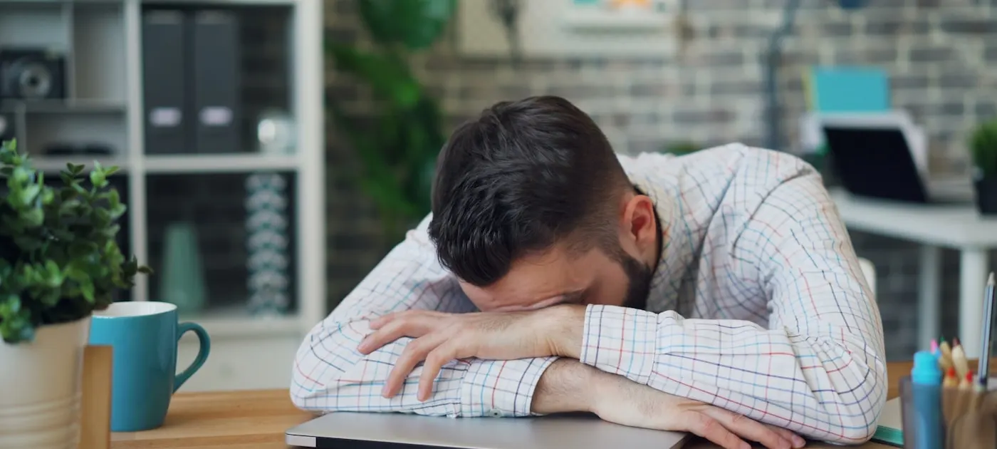a man sitting at a desk with his head in his hands
