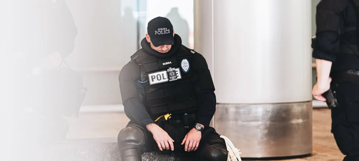 man in black and gray jacket and black pants sitting on brown wooden floor