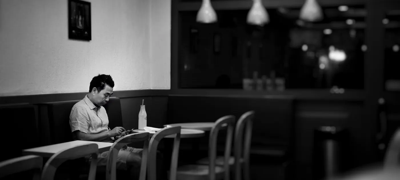 man sitting on cafe while holding smartphone