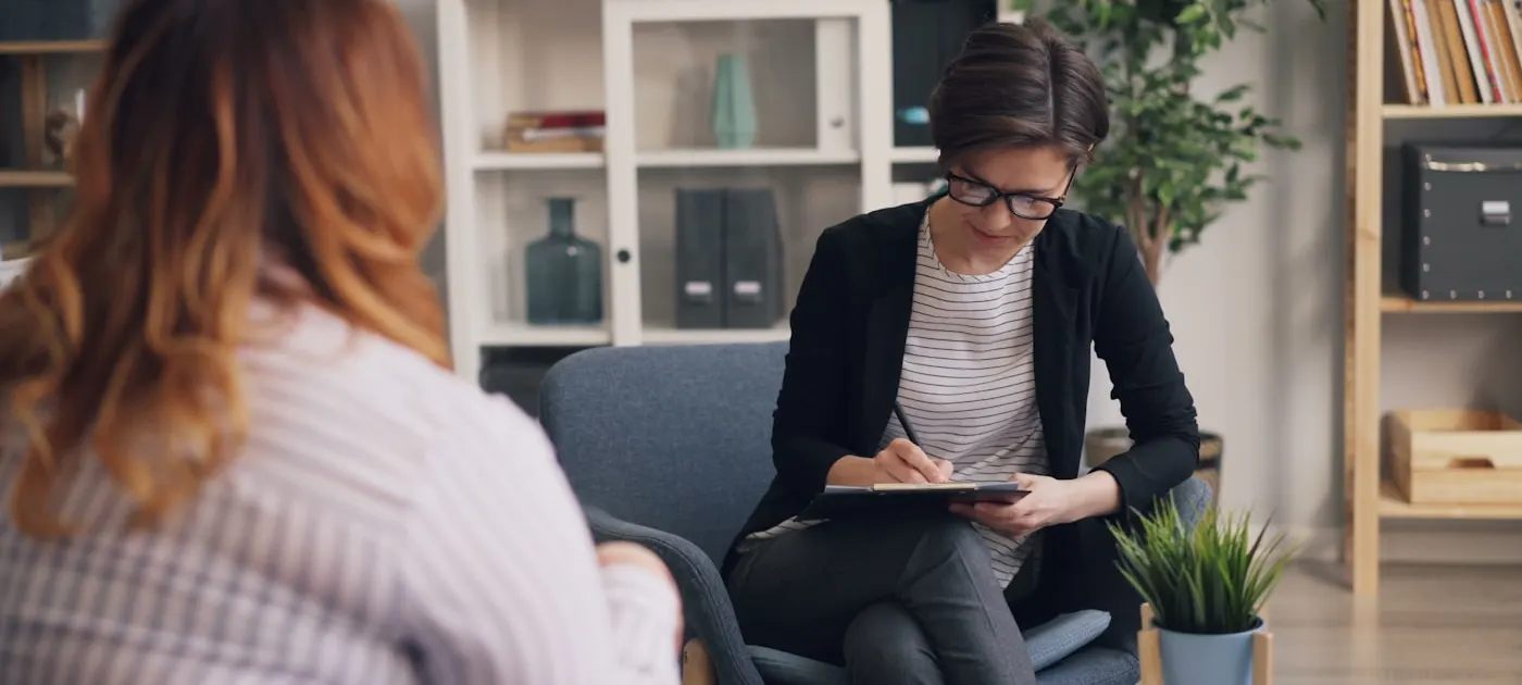 a woman sitting on a couch with a clipboard in her hand