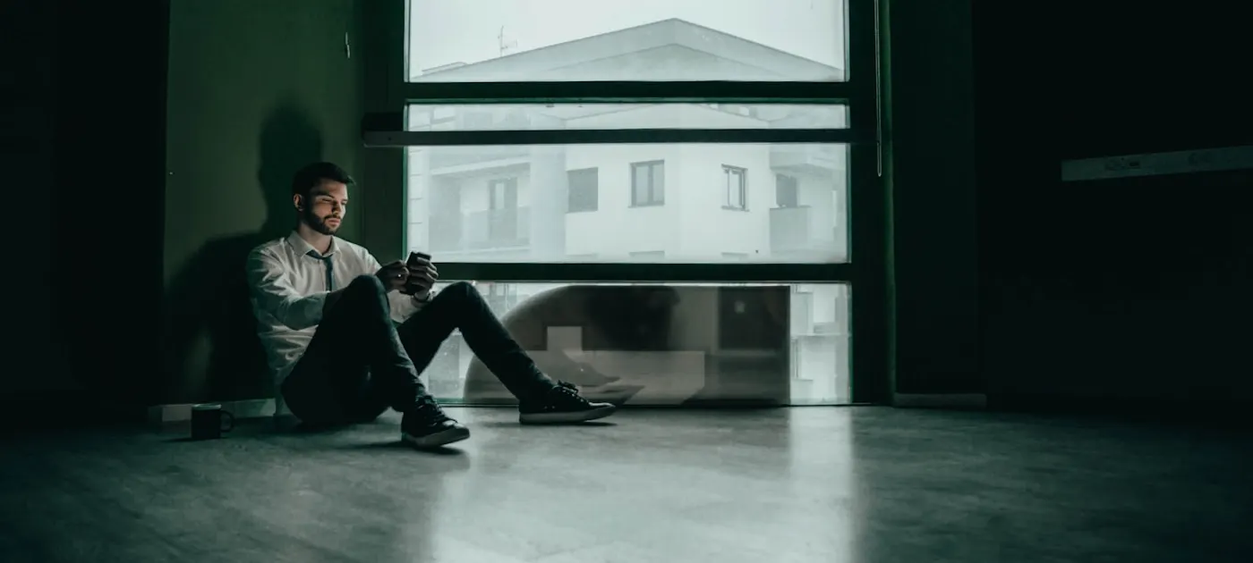 a man sitting on the floor looking at his cell phone