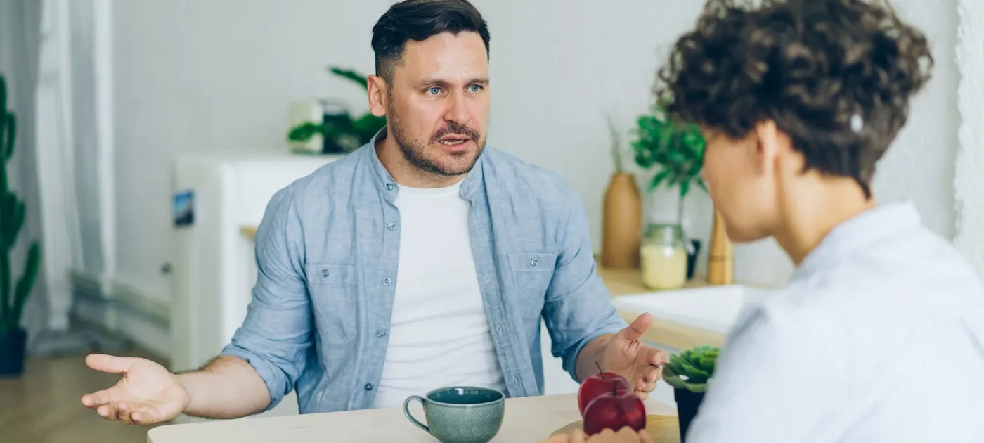 a man sitting at a table talking to a woman